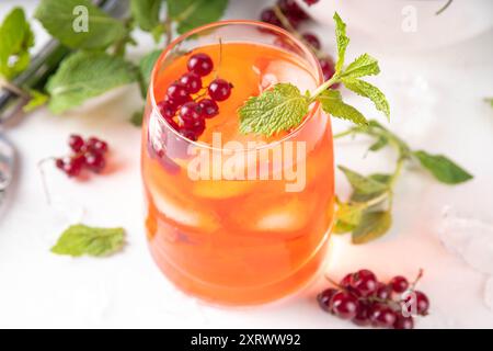 Caipirinha al ribes rosso, limonata o sangria con cubetti di ghiaccio e succo di lime, su un tavolo da cucina bianco spazio copia Foto Stock