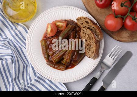 Stufato saporito con okra, salsa di pomodoro e pane su un tavolo bianco, piatto Foto Stock