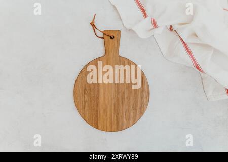 Tagliere in legno vuoto con tovagliolo su tavolo in pietra grigia, vista dall'alto, spazio per copia. Tagliere in legno su sfondo bianco in cemento. Foto Stock