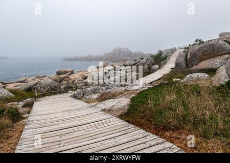 Sentiero in legno attraverso le scogliere di San Vicente do Mar in una nebbiosa giornata estiva a Pontevedra, Galizia, Spagna. Foto Stock