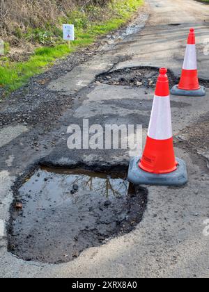 Le buche sono un argomento caldo nel Regno Unito in questo momento. Anni di negligenza, a causa delle carenze di finanziamenti nell'amministrazione locale, hanno lasciato molte delle nostre strade in uno stato pericoloso. E la situazione è stata ulteriormente aggravata da un clima sempre più irregolare, a causa del cambiamento climatico. Qui vediamo alcuni brutti esempi, nel mio villaggio di casa, Radley, nell'Oxfordshire. Questi chasms sono autouccidenti; il mio veicolo ha dovuto essere riparato due volte - a spese considerevoli - a causa della deformazione del tracciamento, delle sospensioni e dei mozzi in lega danneggiati. Assicurazione. Non va bene! Nota il segnale di avvertimento divertente - e falso -. Qualcuno, nonostante tutto, ha un se Foto Stock