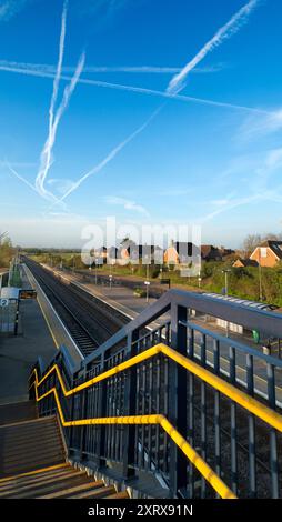 Radley è fortunato ad essere un piccolo villaggio con una stazione ferroviaria principale, che lo collega a Londra, Oxford e le Midlands. E qui, visto dal ponte della stazione sui binari, vediamo una linea di lampioni e una serie di telecamere di sicurezza che si affacciano sulla piattaforma. Il cielo primaverile è pieno di contrafforti che si estendono in blu. Foto Stock