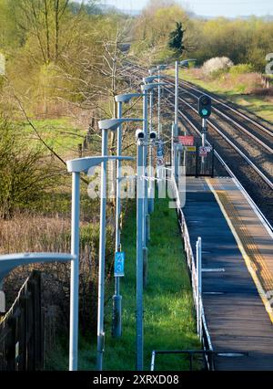 Radley è fortunato ad essere un piccolo villaggio con una stazione ferroviaria principale, che lo collega a Londra, Oxford e le Midlands. E qui, visto dal ponte della stazione sui binari, vediamo una linea di lampioni e una telecamera di sicurezza onnipresente che si affaccia sulla piattaforma. Foto Stock