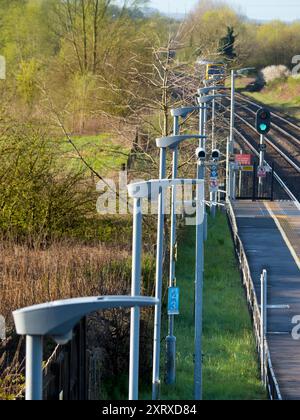 Radley è fortunato ad essere un piccolo villaggio con una stazione ferroviaria principale, che lo collega a Londra, Oxford e le Midlands. E qui, visto dal ponte della stazione sui binari, vediamo una linea di lampioni e una telecamera di sicurezza onnipresente che si affaccia sulla piattaforma. Foto Stock