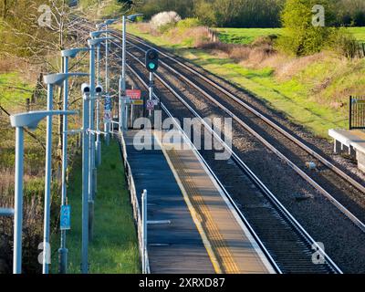 Radley è fortunato ad essere un piccolo villaggio con una stazione ferroviaria principale, che lo collega a Londra, Oxford e le Midlands. E qui, visto dal ponte della stazione sui binari, vediamo una linea di lampioni e una telecamera di sicurezza onnipresente che si affaccia sulla piattaforma. Foto Stock