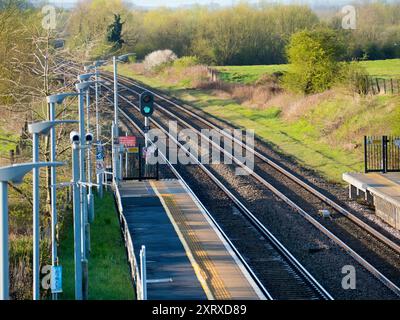 Radley è fortunato ad essere un piccolo villaggio con una stazione ferroviaria principale, che lo collega a Londra, Oxford e le Midlands. E qui, visto dal ponte della stazione sui binari, vediamo una linea di lampioni e una telecamera di sicurezza onnipresente che si affaccia sulla piattaforma. Foto Stock