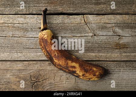 Banana troppo matura con macchie scure sul tavolo di legno, vista dall'alto Foto Stock