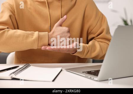 Giovane che usa il linguaggio dei segni durante le videochiamate in casa, primo piano Foto Stock