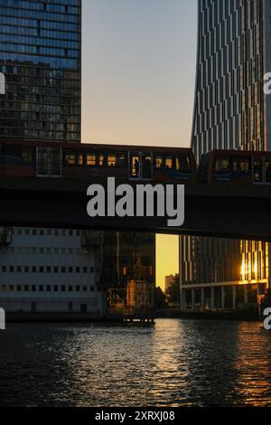 Treno DLR sopra South Dock, Canary Wharf al tramonto Foto Stock