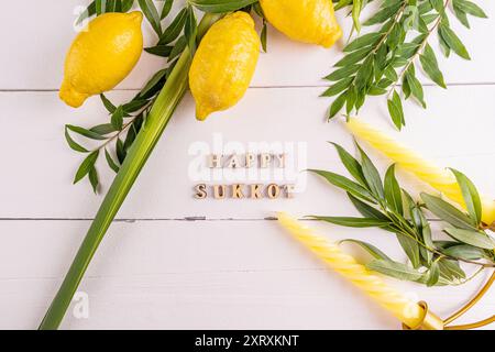 Uno splendido sfondo festivo per la festa del raccolto ebraico di Sukkot con simboli e candele tradizionali. sfondo bianco in legno. Foto Stock