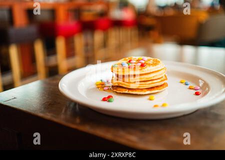 Lenticchie colorate al cioccolato che ricoprono una morbida pila di pancake Foto Stock