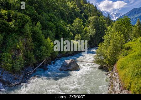 si trova sul fiume dora baltea con bosco in valle d'aosta con il massiccio del monte bianco sullo sfondo e cielo azzurro e soleggiato e nuvoloso Foto Stock