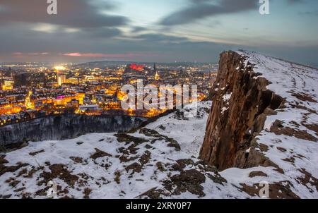 Vista di Edimburgo, Scozia, coperta di neve dall'Arthur Seat al tramonto, con luci stradali che illuminano la città Foto Stock