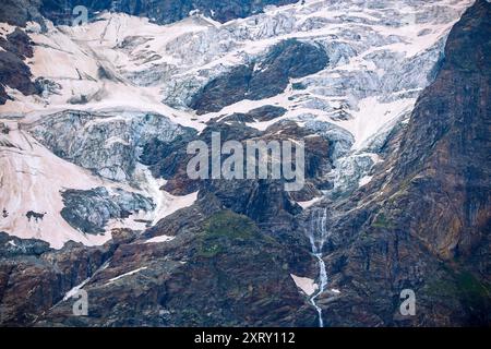 vista di un piccolo ghiacciaio che si scioglie coperto di neve e polvere marrone del sahara sul cervino dalla valle d'aosta in estate Foto Stock