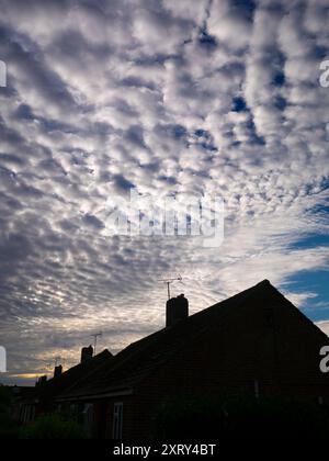 La prima luce con il suggestivo paesaggio altocumulus sopra il mio villaggio natale, Radley, nell'Oxfordshire, illumina case e tetti. Mi piace guardare il cielo. Quello che vedi è spesso bello, e in continuo cambiamento; non vedi mai lo stesso cielo due volte. Camminando per la maggior parte dei posti, di solito sembro essere l'unica persona che guarda in alto; tutti gli altri sono a testa bassa, e si occupano dei loro affari quotidiani. Non sanno cosa si stanno perdendo... Foto Stock