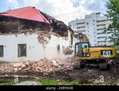 Voronezh, Russia - 2 agosto 2023: Demolizione della vecchia casa a due piani con l'escavatore Foto Stock