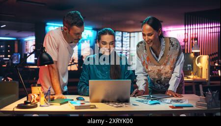 Gruppo di giovani uomini d'affari di successo che partecipano a una riunione di gruppo in Creative Agency utilizzando un computer portatile. Un team diversificato entusiasta sta discutendo un nuovo piano di marketing digitale in un ufficio creativo Foto Stock