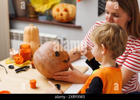 Mamma e bambino decorano insieme la zucca Foto Stock