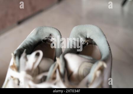 Primo piano di sneakers ben usate, che mettono in risalto l'usura, rappresentando la tendenza principale del sottoconsumo incentrata sulla sostenibilità e sulla consapevolezza Foto Stock