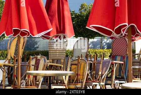 sedie da bistrot sotto gli ombrelli rossi Foto Stock