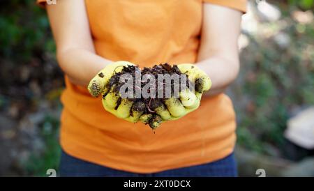 Un contadino tiene in mano i vermi rossi più agghiaccianti Foto Stock