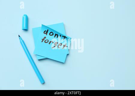 Nota adesiva con testo DA NON DIMENTICARE e penna con punta in feltro su sfondo blu Foto Stock