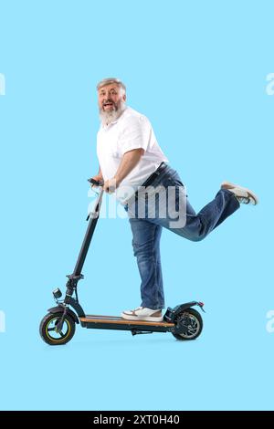 Uomo maturo che guida uno scooter elettrico su sfondo blu Foto Stock