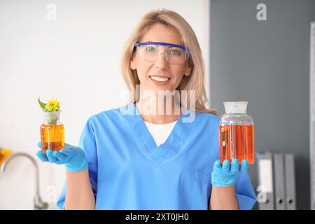 Scienziata felice con matracci di campioni e girasole in laboratorio Foto Stock