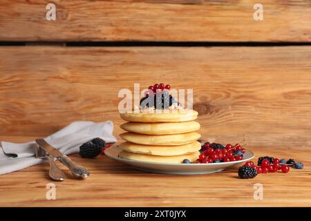 Piatto di frittelle dolci con diversi frutti di bosco freschi su fondo di legno Foto Stock