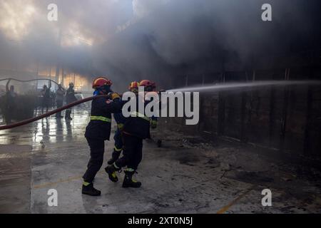 Atene, Grecia, 12 agosto 2024. I vigili del fuoco, aiutati da volontari, spengono l'incendio in un negozio nel sobborgo di Vrilissia, capitale greca. Un incendio che scoppiò a Varnavas l'11 agosto continuò a infuriare nell'Attica orientale il 12 agosto, si diffuse e si diffuse su un fronte che si estendeva per più di 20 chilometri. Diversi paesi hanno risposto positivamente alla richiesta delle autorità greche di assistenza da parte del meccanismo di protezione civile dell'UE (EUCPM) per combattere l'infuria degli incendi. Crediti: Dimitris Aspiotis/Alamy Live News Foto Stock