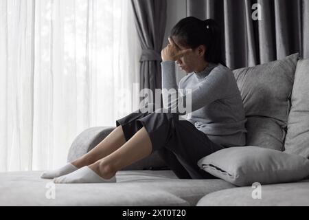 Soffre di depressione, problemi di salute mentale. giovane donna asiatica seduta sul divano sentirsi depressa. Le donne sono stressate e depresse. Foto Stock