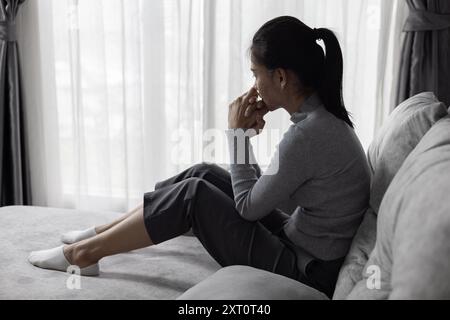 Soffre di depressione, problemi di salute mentale. giovane donna asiatica seduta sul divano sentirsi depressa. Le donne sono stressate e depresse. Foto Stock