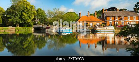 Saint Helen's Wharf è un famoso luogo di bellezza sul Tamigi, appena a monte del ponte medievale di Abingdon-on-Thames. Il molo è stato per secoli un importante collegamento di trasporto e trasporto marittimo sul Tamigi e tra i canali da Oxford e le Midlands. Belle case mercantili si incrociano con case di elemosina e la chiesa di Sant'Elena di epoca sassone. Qui vedremo imbarcazioni da diporto e case ormeggiate lungo le Long Alley Alms Houses, viste in una bella giornata di mezza estate dalla riva nord del fiume. Foto Stock