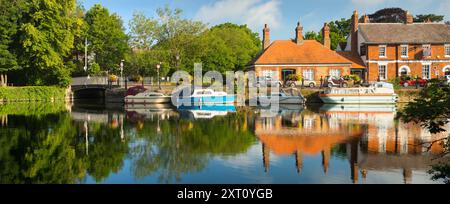 Saint Helen's Wharf è un famoso luogo di bellezza sul Tamigi, appena a monte del ponte medievale di Abingdon-on-Thames. Il molo è stato per secoli un importante collegamento di trasporto e trasporto marittimo sul Tamigi e tra i canali da Oxford e le Midlands. Belle case mercantili si incrociano con case di elemosina e la chiesa di Sant'Elena di epoca sassone. Qui vedremo imbarcazioni da diporto e case ormeggiate lungo le Long Alley Alms Houses, viste in una bella giornata di mezza estate dalla riva nord del fiume. Foto Stock