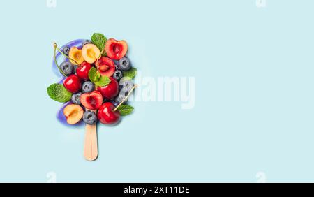 Una variopinta gamma di frutta fresca disposta a forma di popsicle su uno sfondo blu pastello. Foto Stock