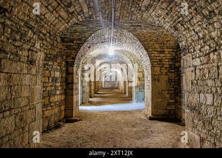 Tunnel interno nella fortezza di Charlemont, mura, volta ad arco e pilastri in pietra, illuminati da luce artificiale dalle lampade, giorno d'estate nel dipartimento delle Ardenne Foto Stock