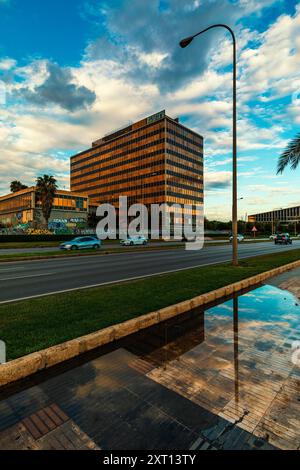 City ​​road, edificio moderno e lampada da strada sotto il bellissimo cielo che si riflette in una pozzanghera dopo la pioggia a Palma, Spagna. Foto Stock