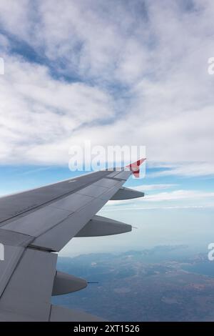 Attraverso la finestra dell'aeromobile, durante il viaggio di giorno, potrai ammirare le nuvole soffici sopra il mare e il terreno Foto Stock