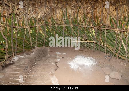 All'interno della capanna con letto di pelle animale e fuoco, tribù degli Hadzabe, cacciatori-raccoglitori, Tanzania Foto Stock