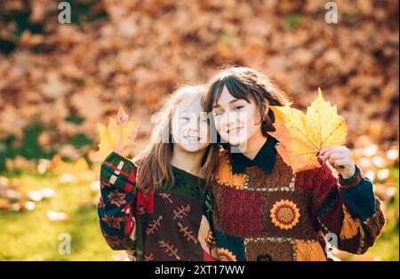 Due sorelle con foglie d'arancia autunnale. Salute e bellezza naturale della donna. Sorridente ragazza con sorella con una foglia d'arancia in mano all'autunno Foto Stock