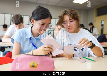 Qingdao, la provincia cinese dello Shandong. 12 agosto 2024. Studenti cinesi e russi realizzano lavori di taglio della carta presso la Qingdao Hengxing University a Qingdao, nella provincia di Shandong della Cina orientale, 12 agosto 2024. Recentemente a Qingdao si è tenuto un campo estivo a tema sull'apprendimento del cinese, con attività per 12 studenti russi che presentano eredità culturali immateriali tradizionali. Crediti: Zhang Ying/Xinhua/Alamy Live News Foto Stock