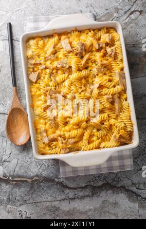 Pasta in casseruola di tonno al forno con salsa cremosa, mais dolce e condimento croccante, cotta fino al primo piano dorato sul piatto da forno sul tavolo. Verticale a. Foto Stock