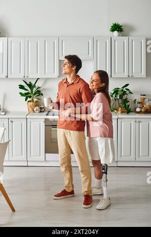 Una coppia sta in cucina, sorridendo e bevendo una tazza di caffè. Foto Stock