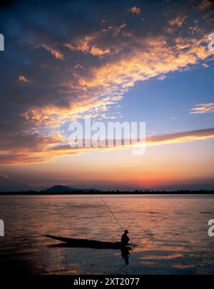 Pescatore sagomato su una barca durante un tramonto vibrante con nuvole sparse nel cielo, il lago dal, Srinagar, Kashmir dria00427 Copyright: XCO Foto Stock