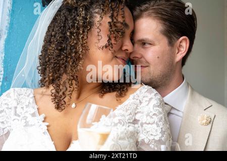 La sposa in un abito in pizzo abbraccia tenermente lo sposo con un abito, entrambi sorridenti mentre condividono un momento intimo. Panc05937 Copyright: XConnectxImagesx Foto Stock