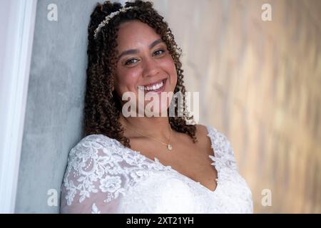 Sposa sorridente in un abito da sposa in pizzo bianco appoggiato a una parete. Panc05963 Copyright: XConnectxImagesx Foto Stock
