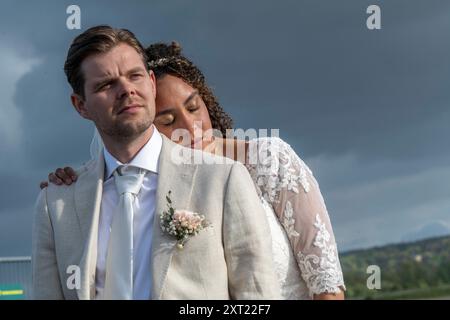 La sposa con i capelli ricci in un abito in pizzo abbraccia lo sposo in un abito leggero sotto un cielo coperto. Panc05984 Copyright: XConnectxImagesx Foto Stock