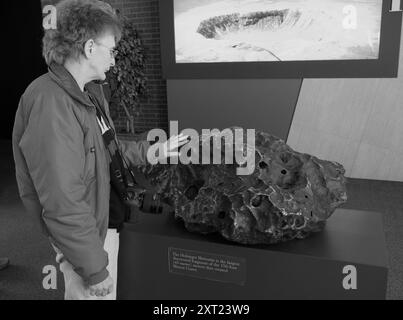 Donna caucasica di età compresa tra i 50 e i 60 anni, sentendo l'Holsinger Meteorite al Meteor Crater, situato sulla Route 66, appena fuori la i-40 vicino a Winslow, Arizona. STATI UNITI Foto Stock