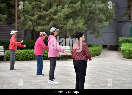 Donne anziane che praticano tai chi in un parco, a Pechino, capitale della Cina, il 19 aprile 2024 Foto Stock