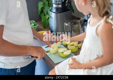 Famiglia con un giovane padre e la sua piccola figlia che preparano frutta per un succo sano o frullato in cucina Foto Stock